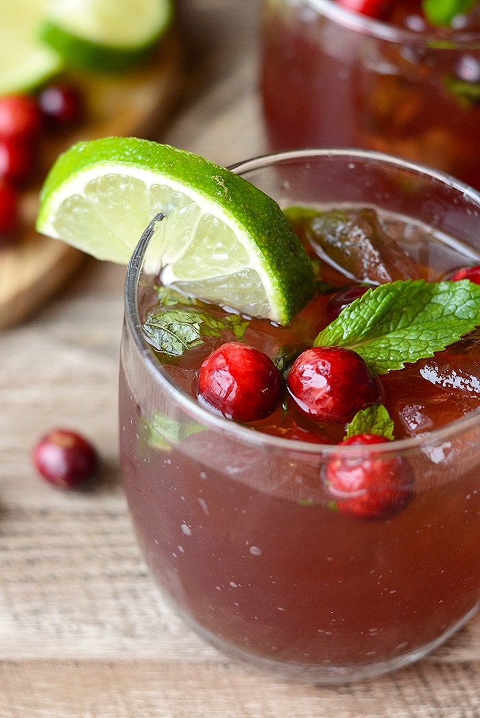 A close up of a cranberry mojito with fresh lime and mint garnish