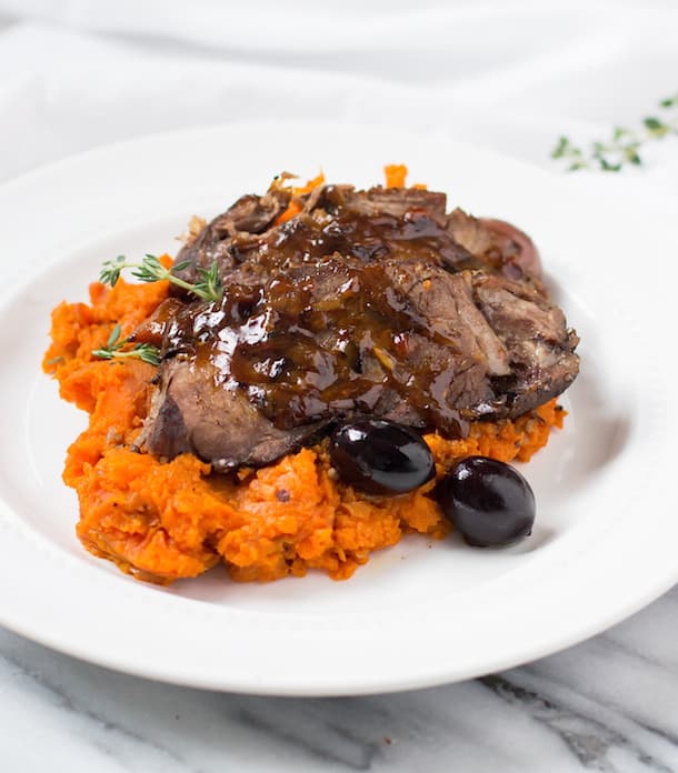 A white plate with slow braised beef and carrot mash