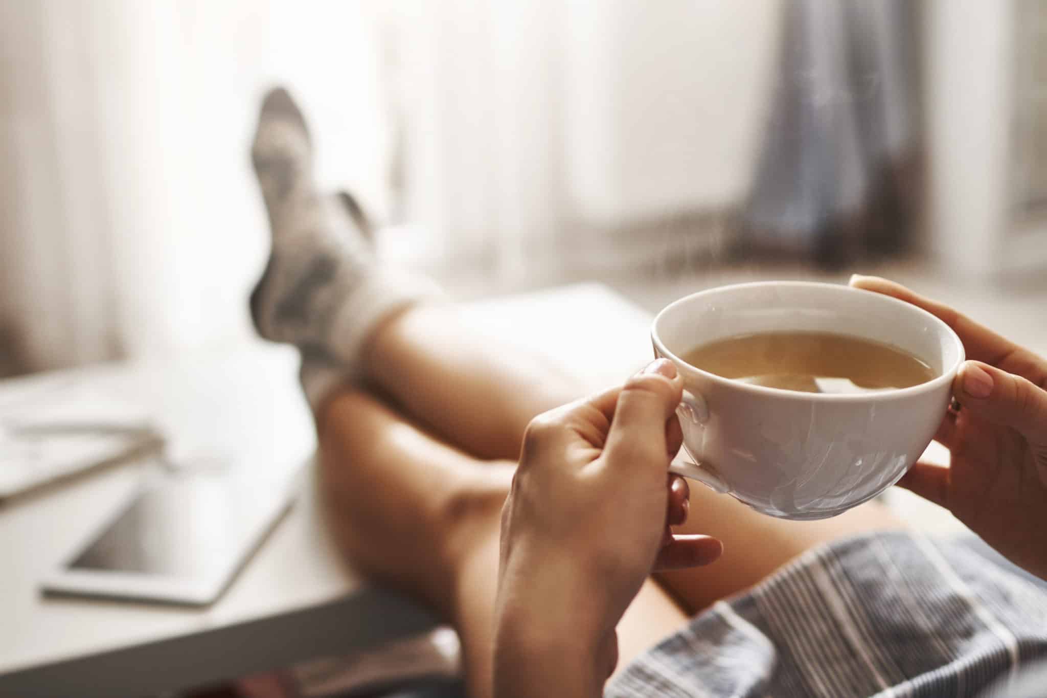 Woman on couch with feet up and a cup of tea