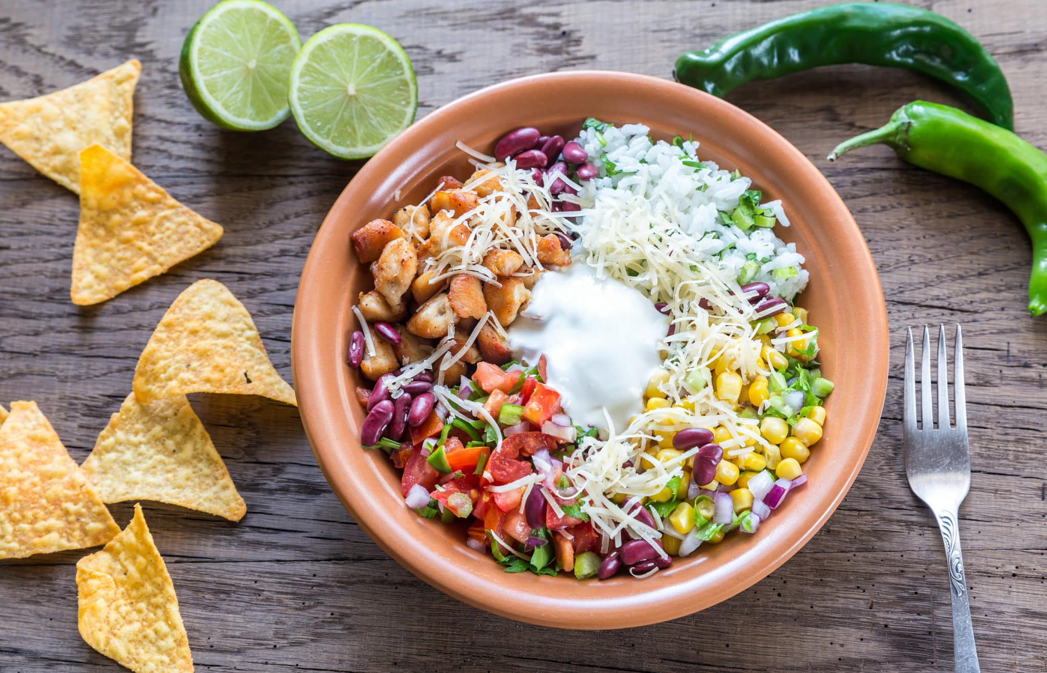Mexican style buddha bowl with chicken, tomatoes, beans, cheese and sour cream