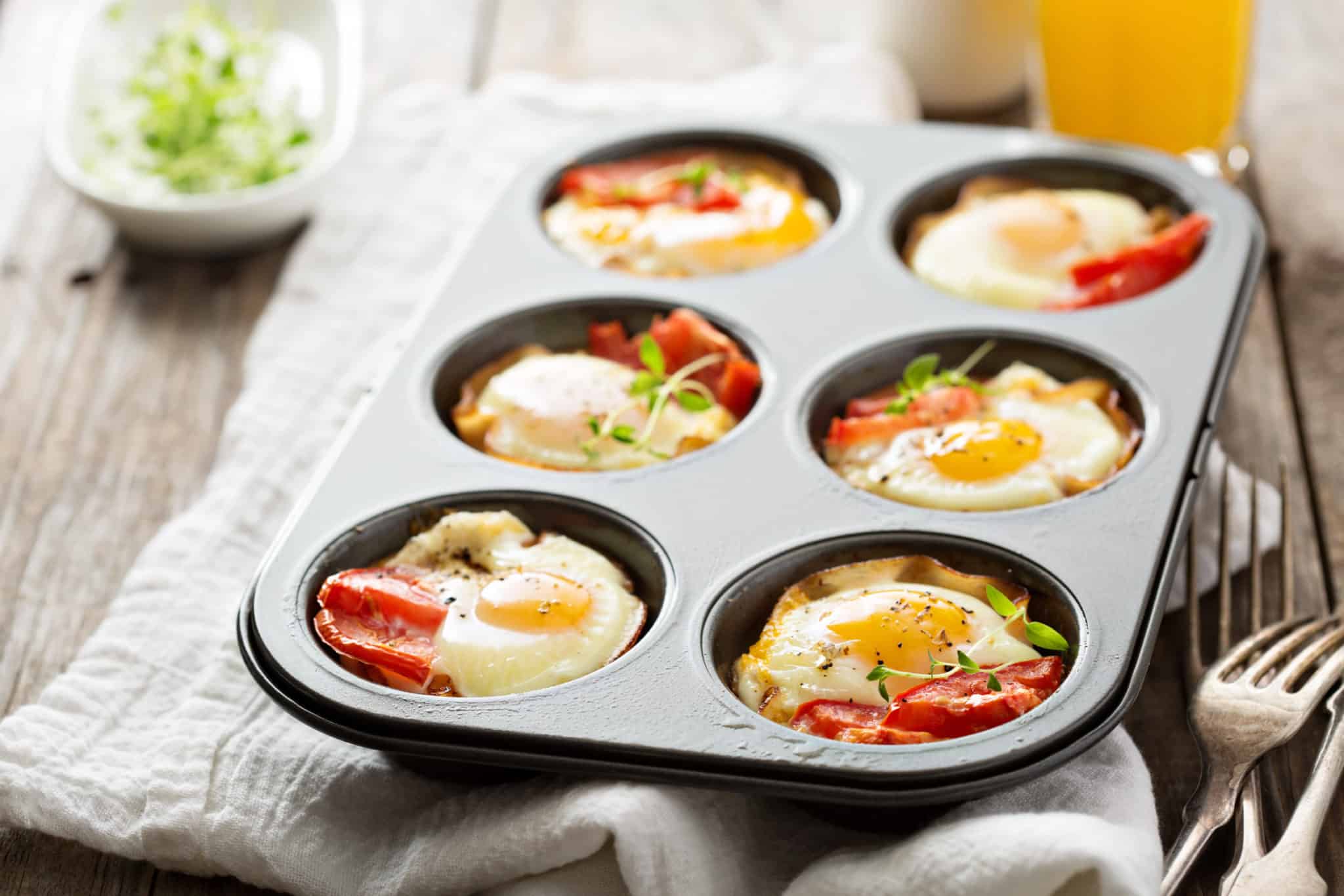 Baked eggs with ham and tomato in muffin tin.