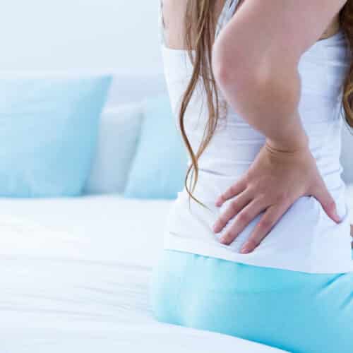 Attractive woman with back pain at home in the bedroom