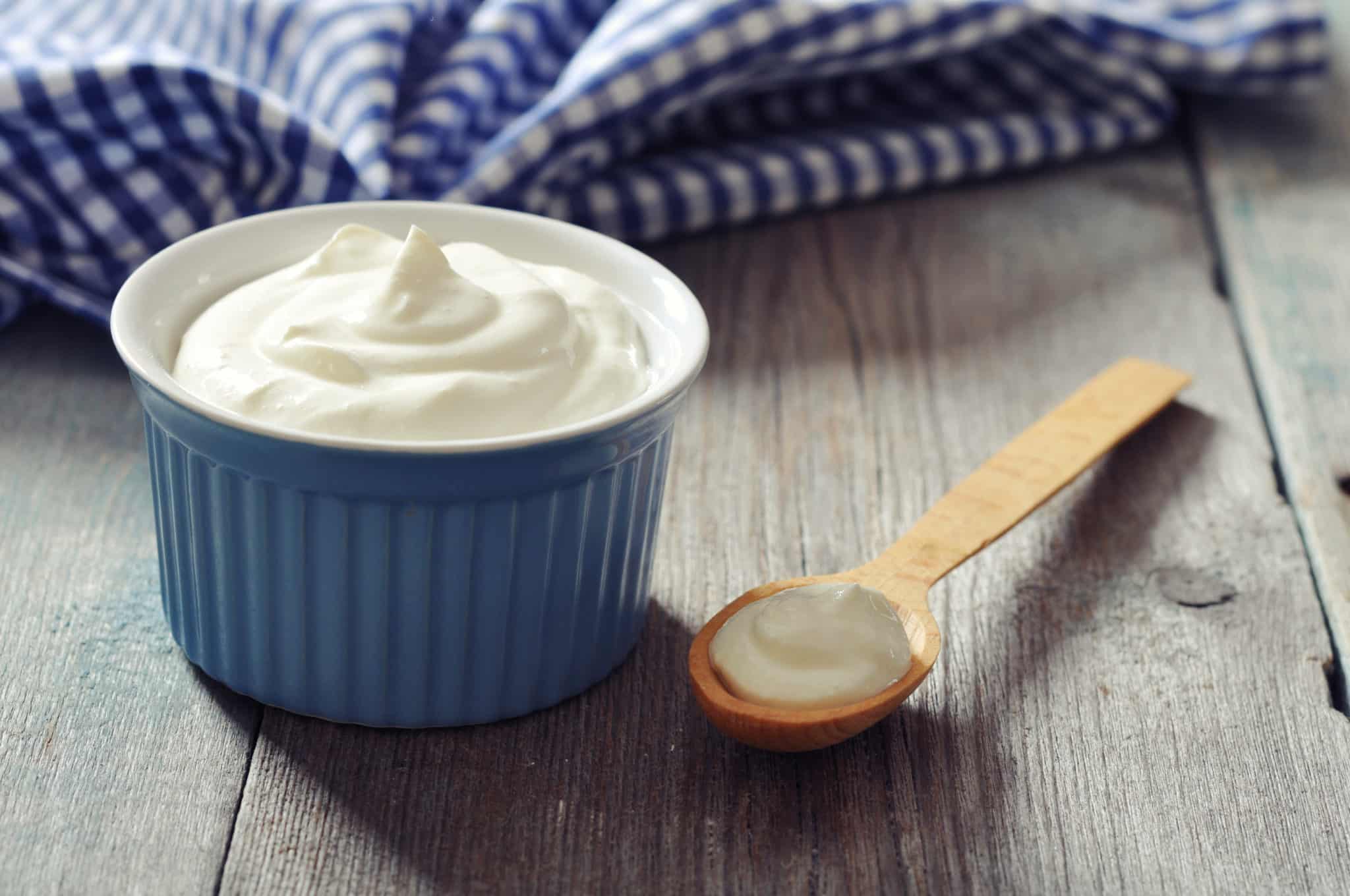 Greek yogurt in a blue bowl with wooden spoon