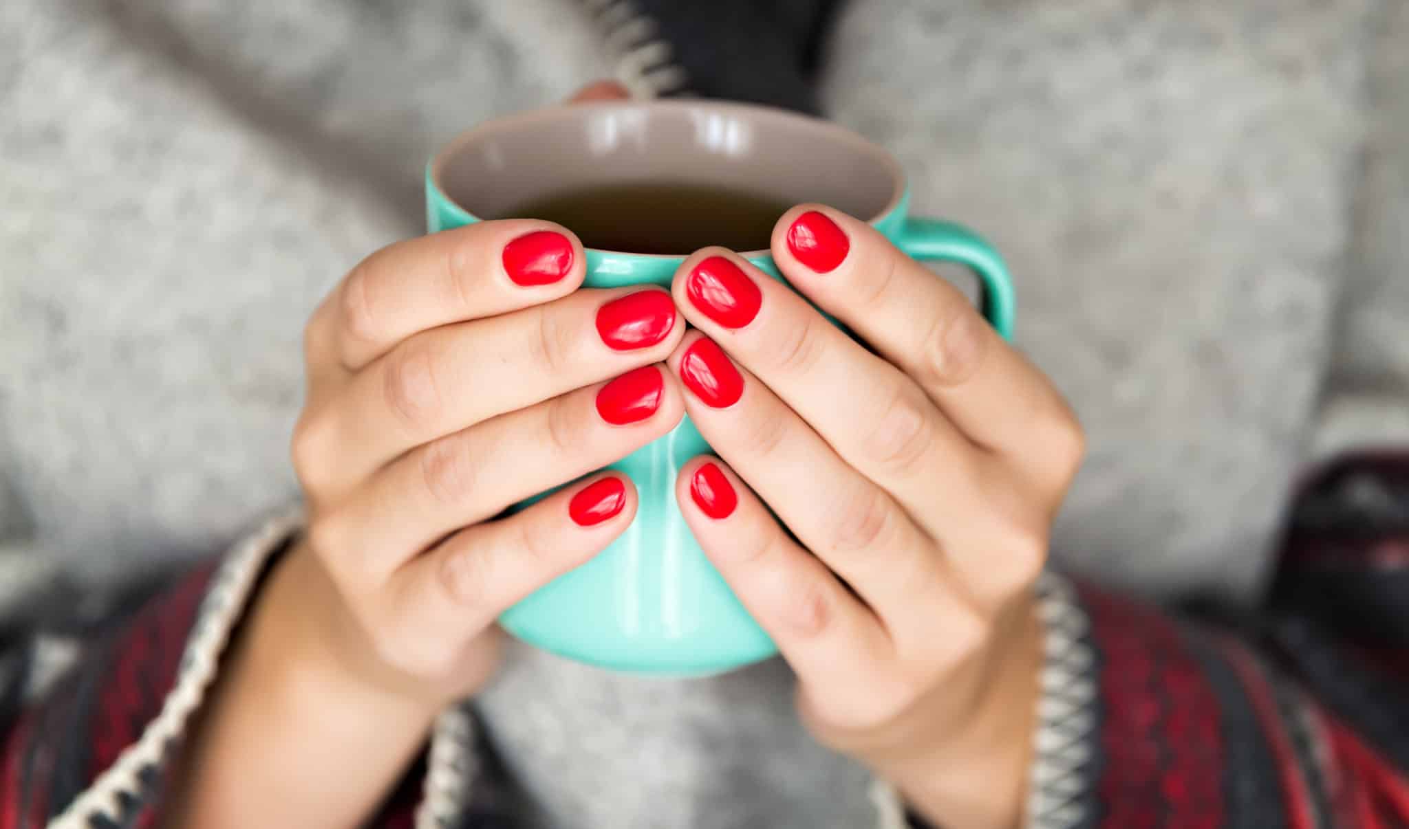 Woman holding coffee cup with red nails