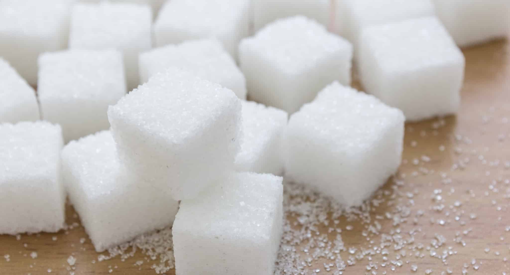 Sugar cubes on wood table discussing the effects of sugar on insulin and weight.