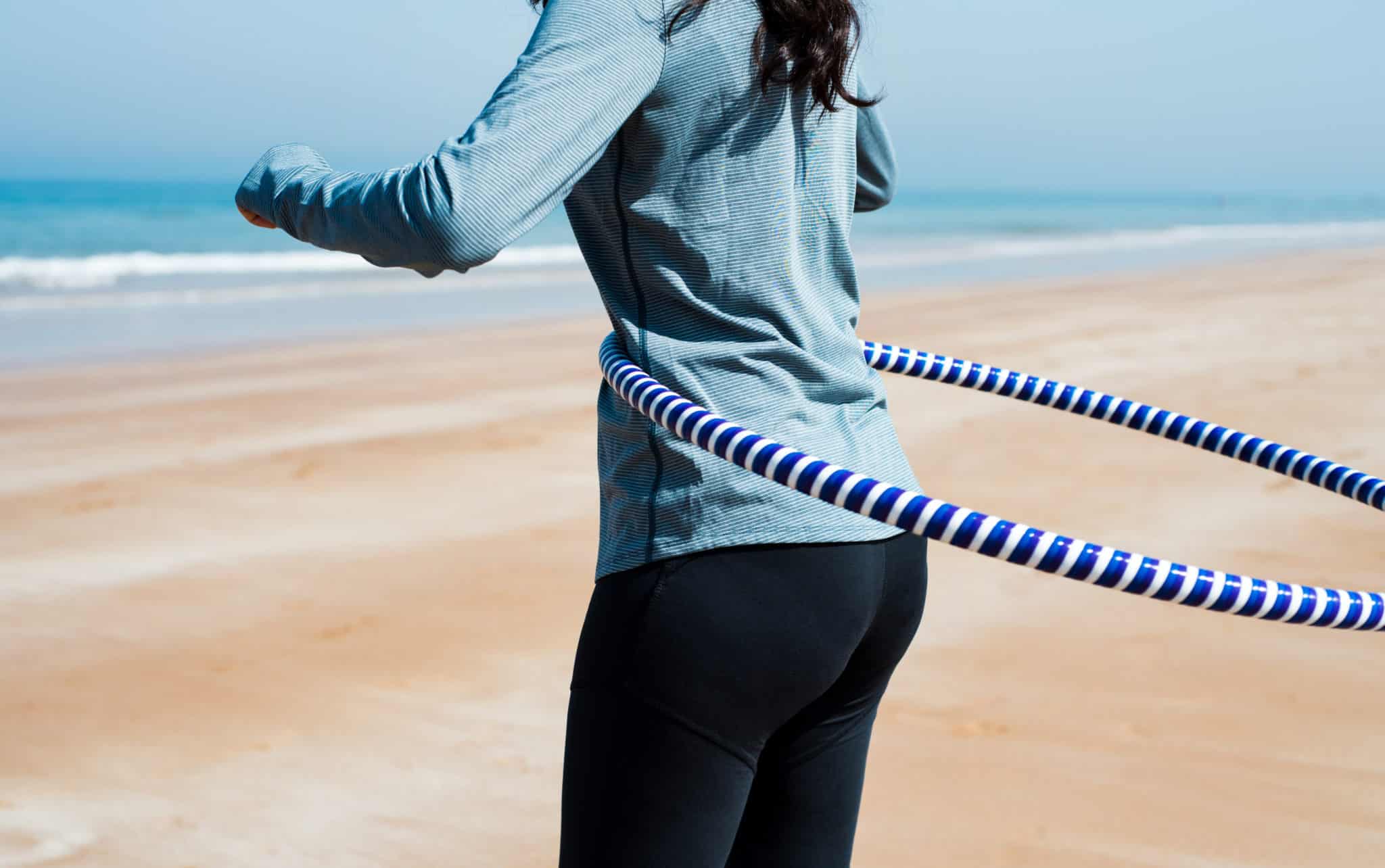 Woman hula-hooping on beach