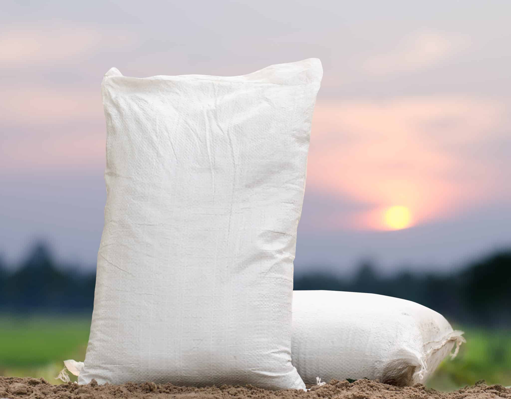 Two sand bags sitting on ground with pretty sky background