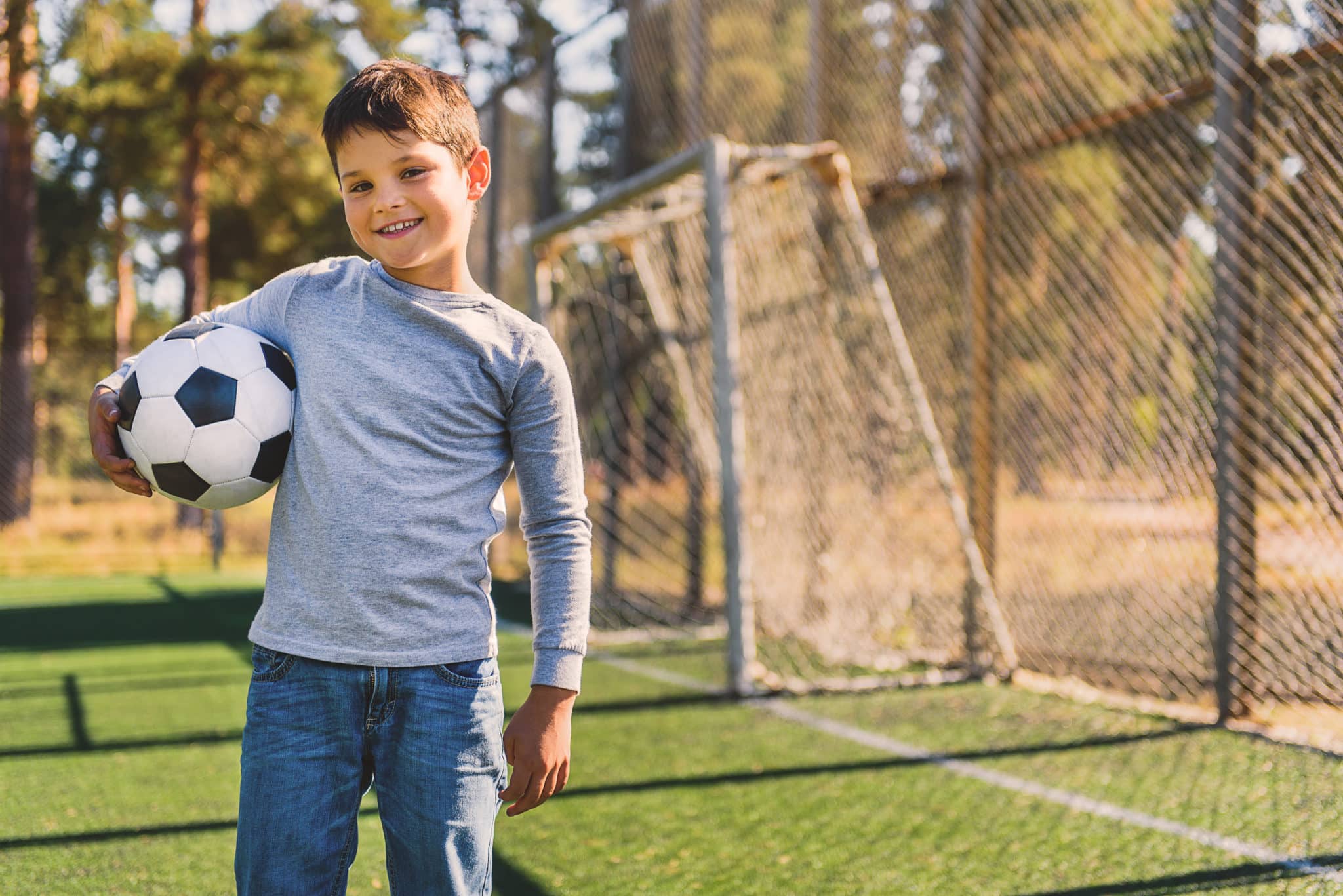Young boy holding soccer ball on soccer field