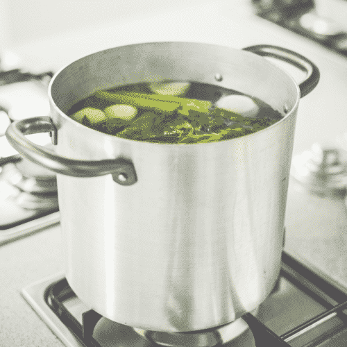 stock pot on stove top with veggies inside