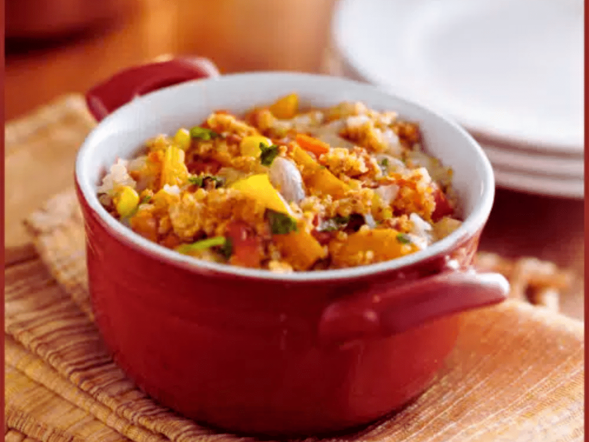 A red casserole dish filled with the chicken quinoa casserole, onions, and peppers.