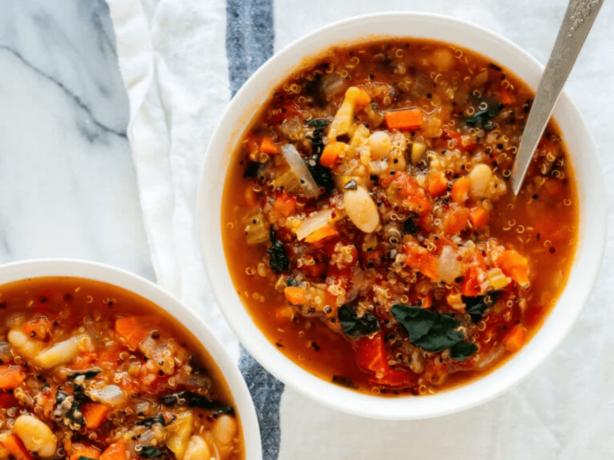 A bird's-eye view of the quinoa vegetable soup loaded with veggies, beans, and kale.