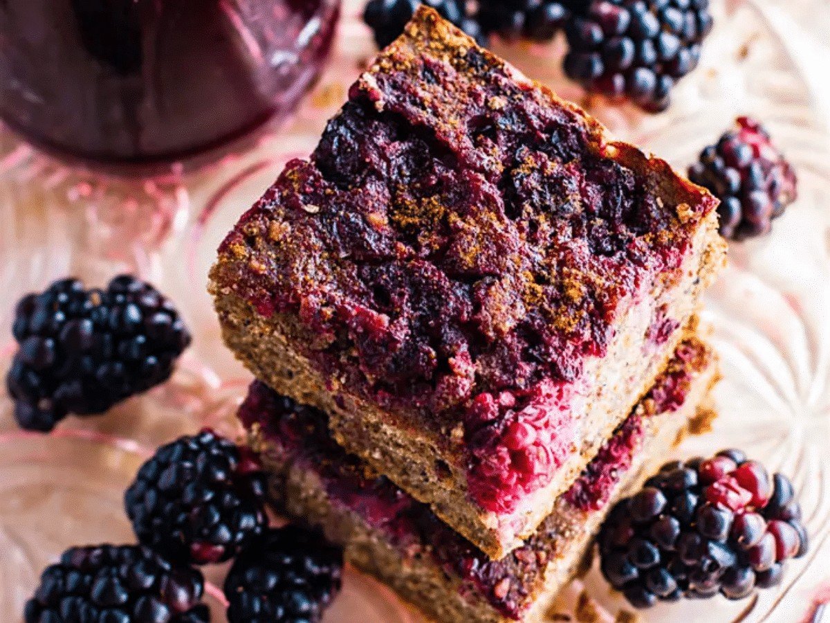 A stack of blender blackberry quinoa cakes surrounded by fresh blackberries.