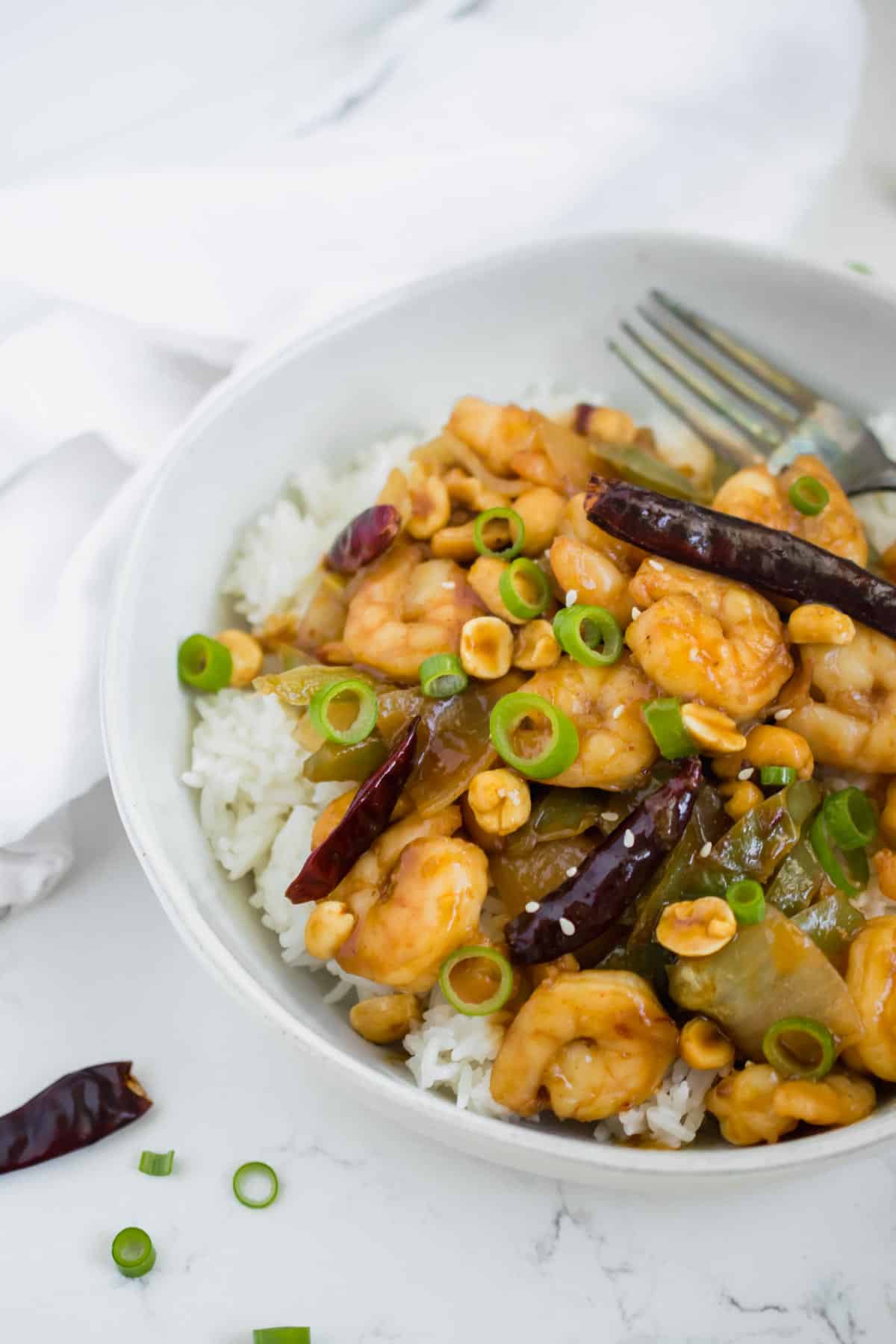 Healthy Kung Pao shrimp recipe in a white bowl with fork
