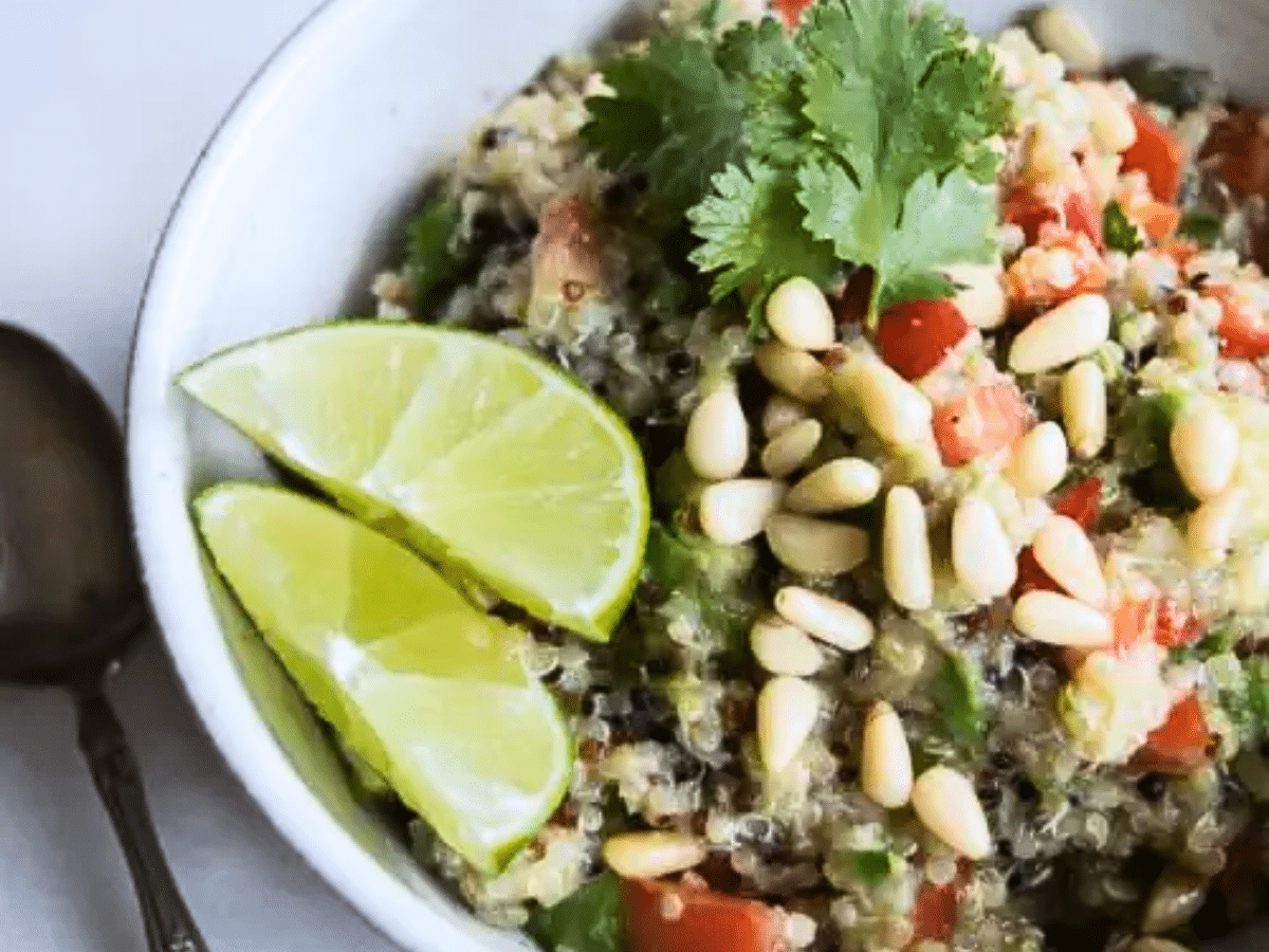 A close-up of the quinoa fiesta bowl topped with fresh cilantro and lime wedges.