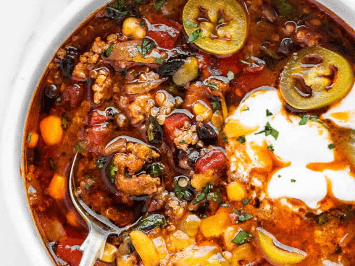 A close-up view of the Mexican quinoa soup filled with chorizo, jalapenos, corn, and veggies.