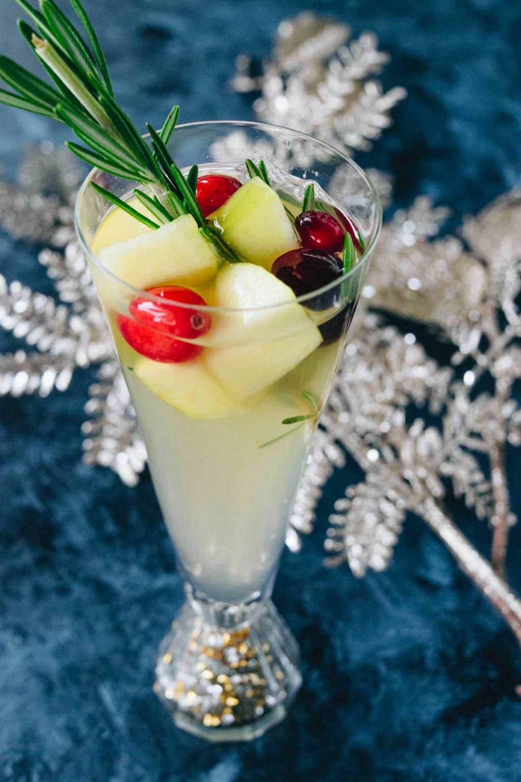 A flute of christmas sangria with cranberry and rosemary garnish