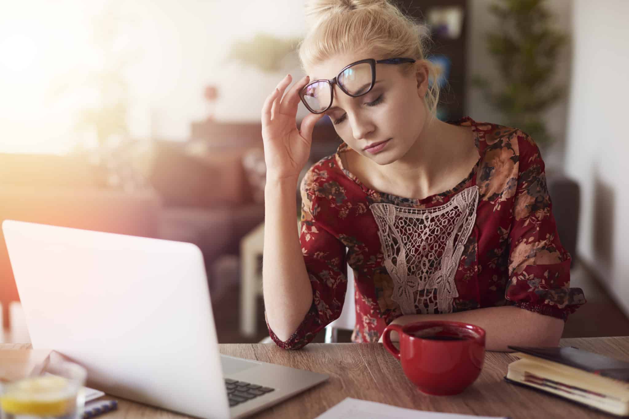 woman with adrenal fatigue wearing glasses by laptop stressed out