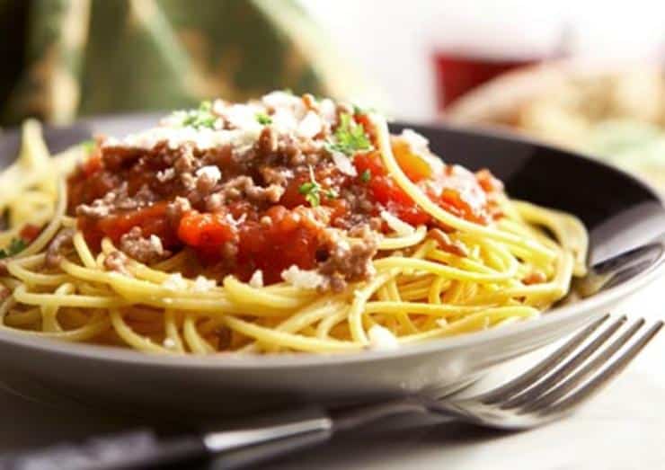 Pasta bolognese on a dark plate with a fork