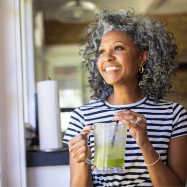 Smiling woman drinking green juice as a part of a healthy morning routine