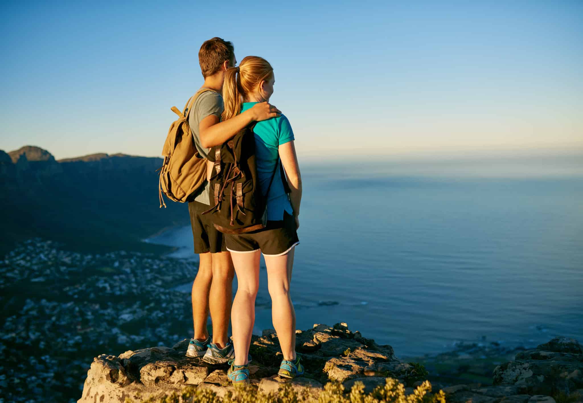 Young couple standing on rock after a hike and looking at the view