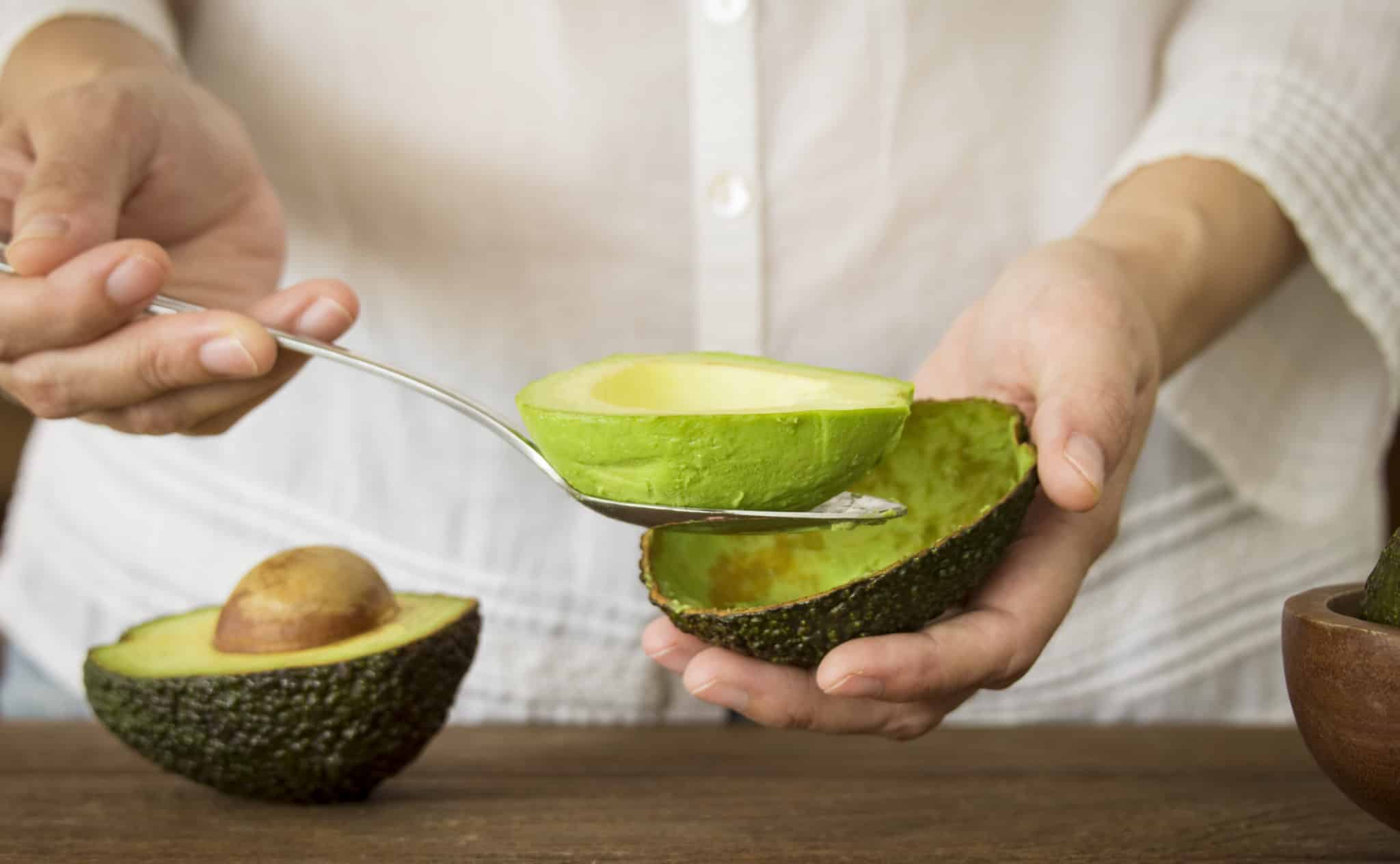 woman scooping avocado out of its shell