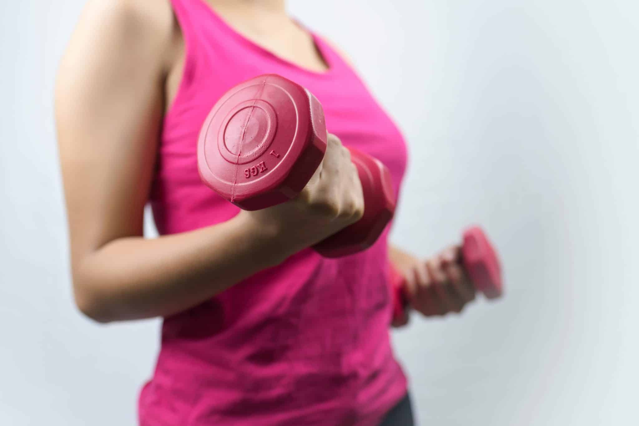 A woman holding pink dumbbells. 