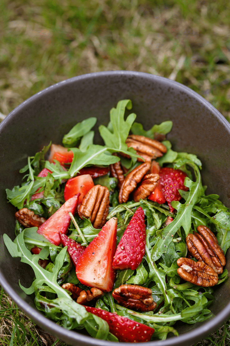 Arugula salad with berries and pecans in a bowl
