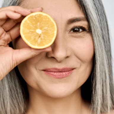 aging womand with good skin and healthy hair holding orange
