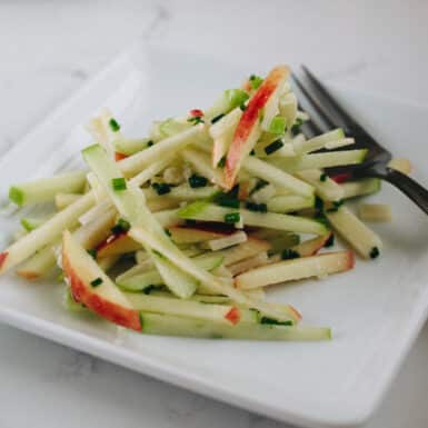 Matchstick apple manchego salad on a white plate with fork