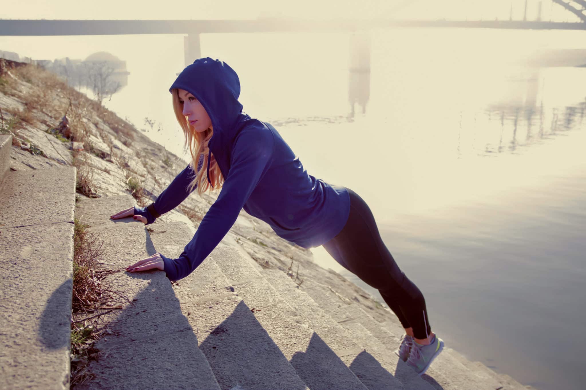 woman doing a push up on a set of stairs in the winter