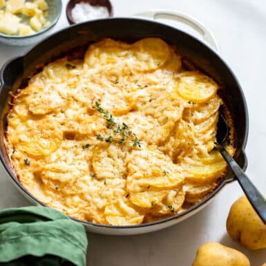 low fat scalloped potatoes in skillet with serving spoon on white counter