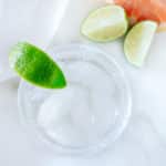 Cocktail glass with tequila and soda, lime and grapefruit wedges