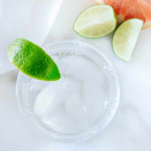 Cocktail glass with tequila and soda, lime and grapefruit wedges