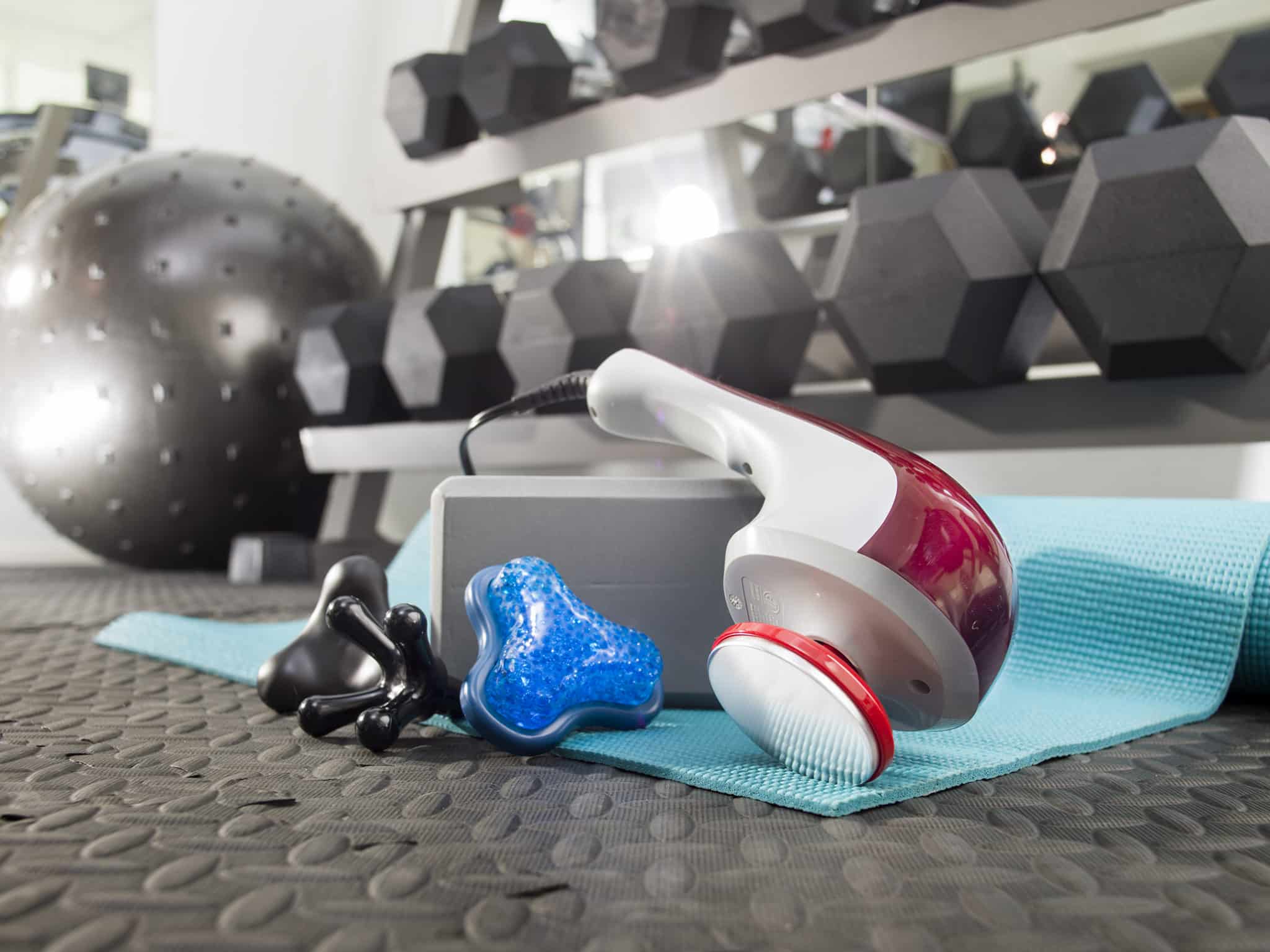Wahl Hot/Cold Therapy Massager laying on gym floor with weights in the background