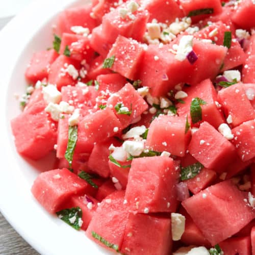 Large white bowl filled with chunked watermelon, mint, feta, and sliced red onion