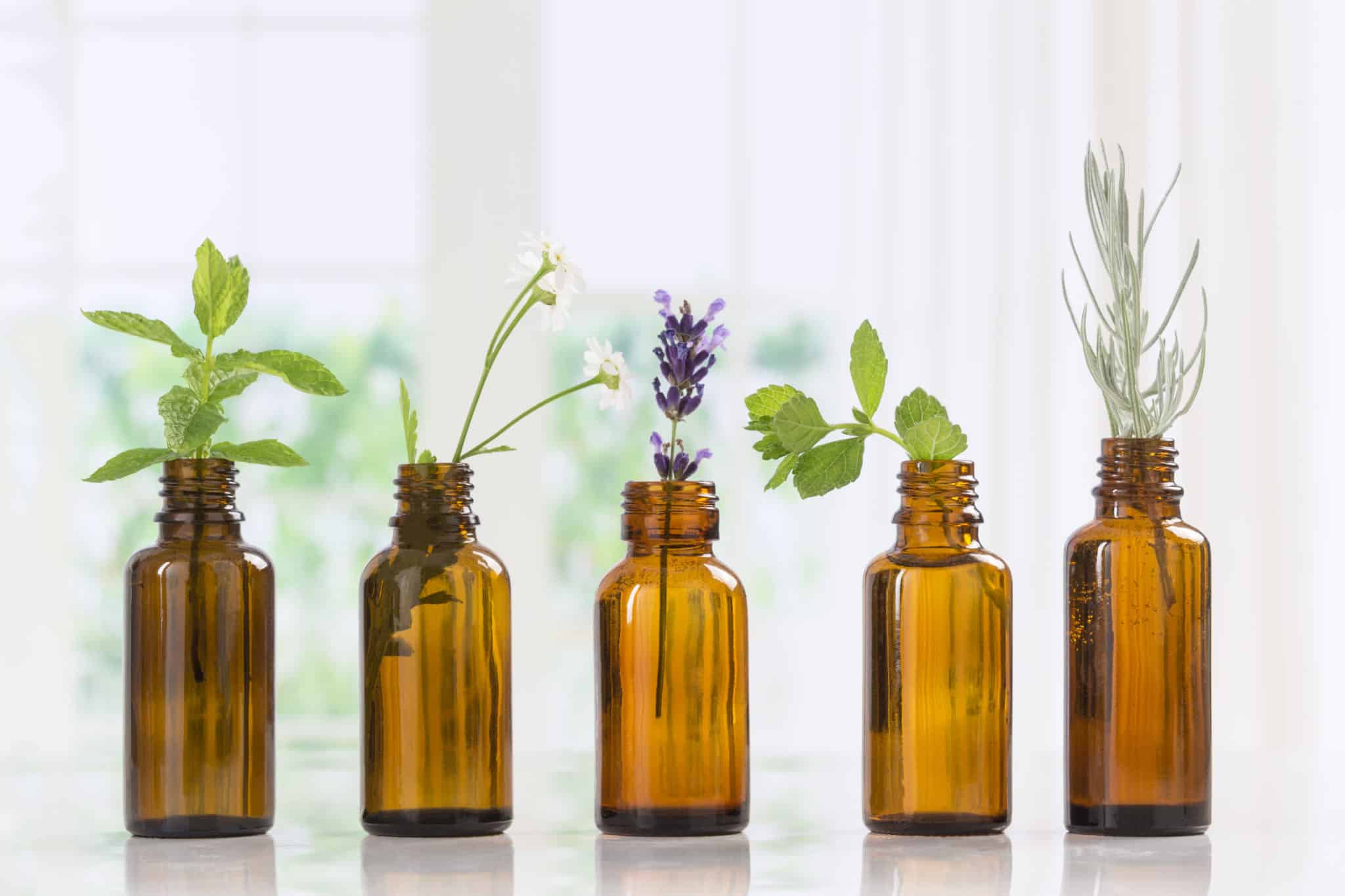 Essential oil bottles with fresh herbs to naturally remedy hot flashes