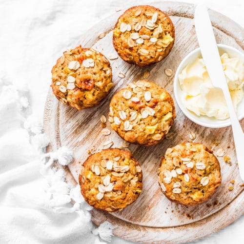 Healthy carrot cake muffins on a wood platter with butter and white table