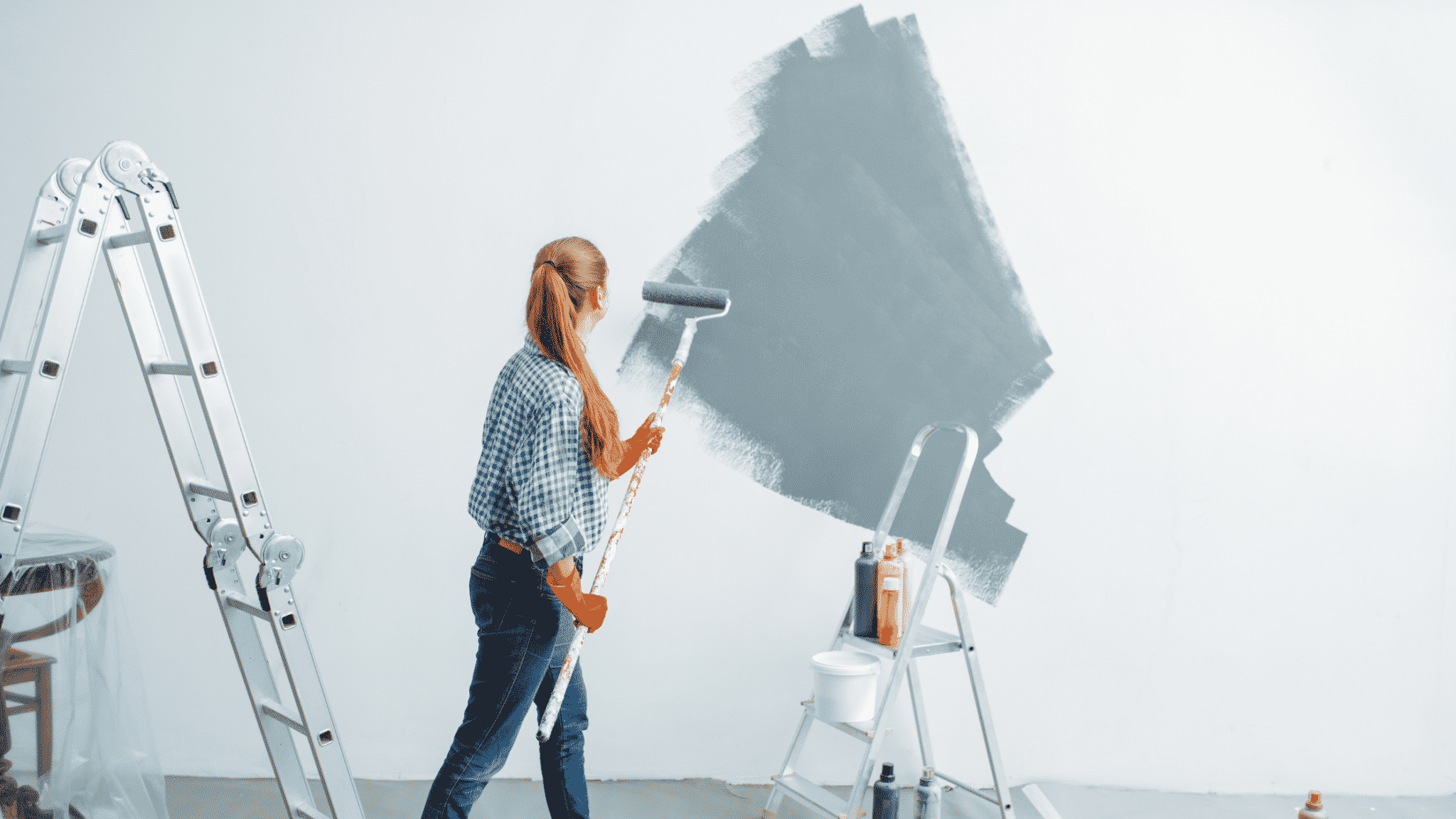 woman rolling gray paint on white walls