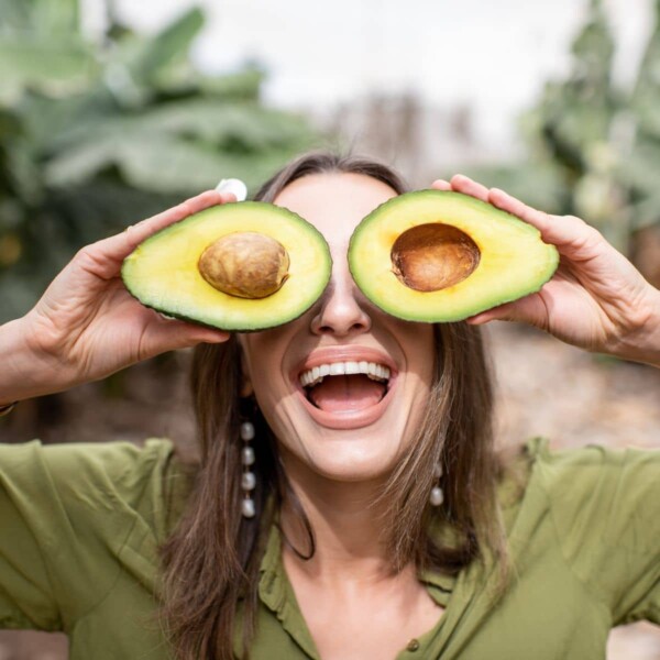 woman holding heart healthy fat avocados over eyes