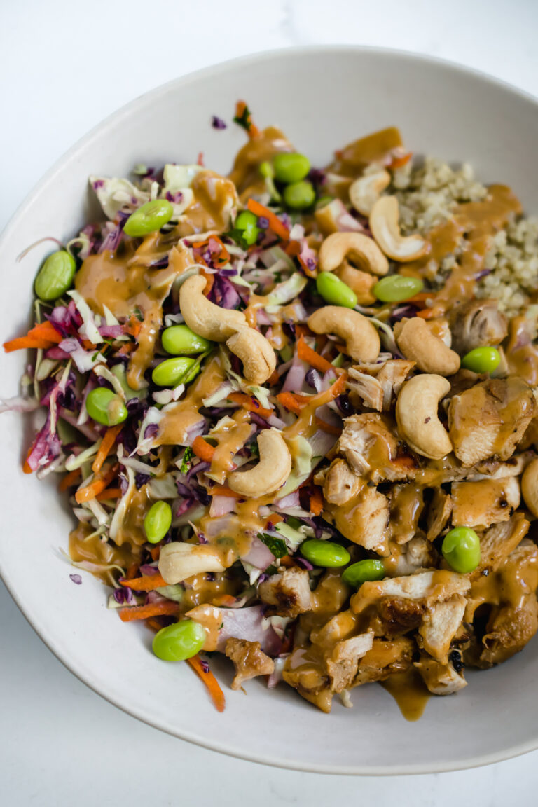 A gluten-free, dairy-free crunchy thai salad with quinoa and chicken in a bowl sprinkled with cashews and edamame
