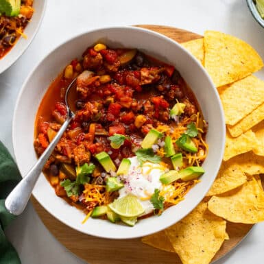 serving of healthy turkey chili with spoon and chips on side