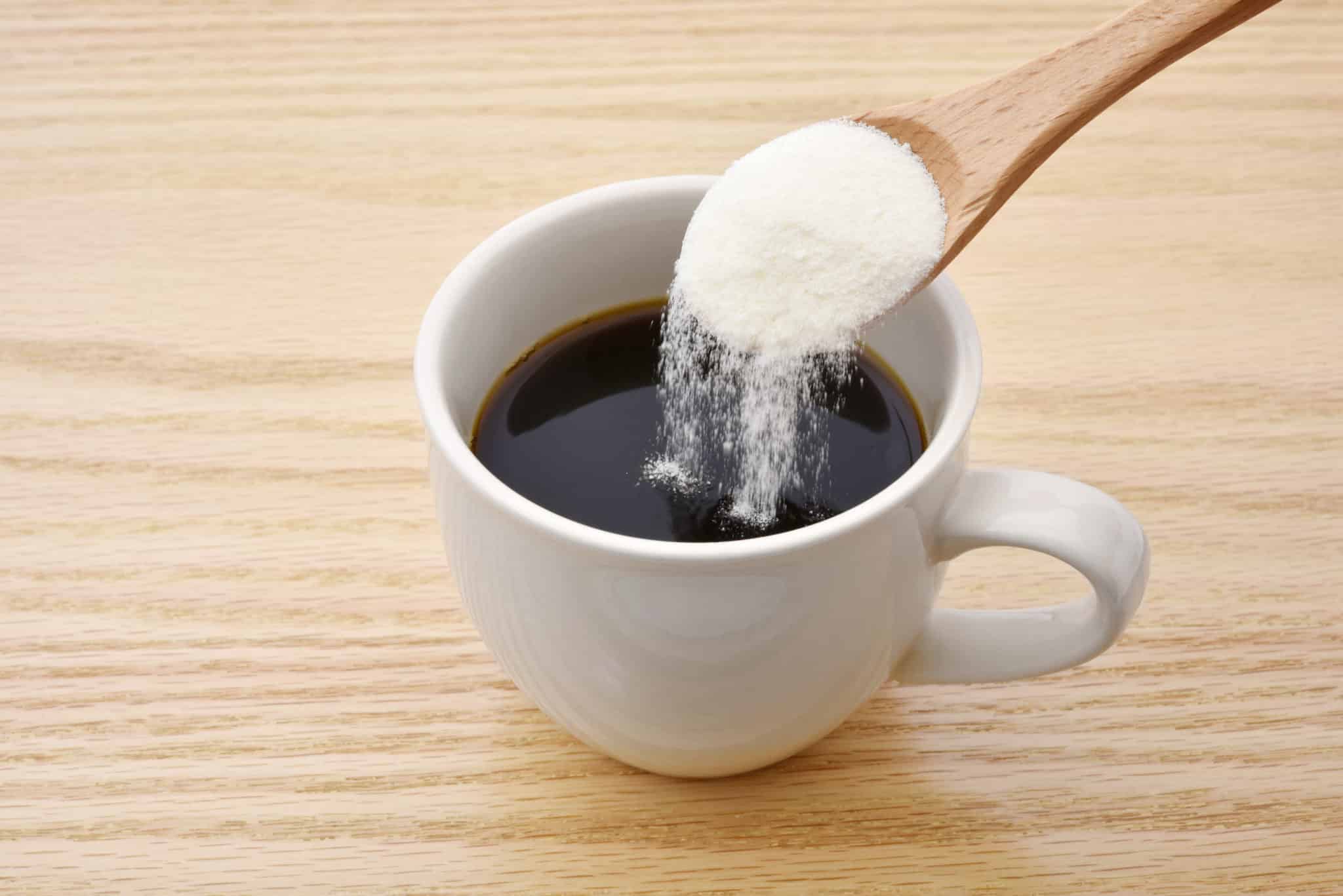 Collagen powder on spoon being poured into coffee