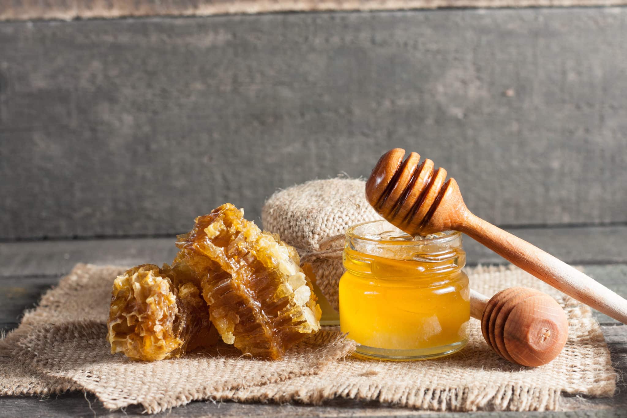 Jar of honey next to honeycomb pieces