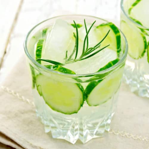 Cocktail glass with cucumbers and herb sprig