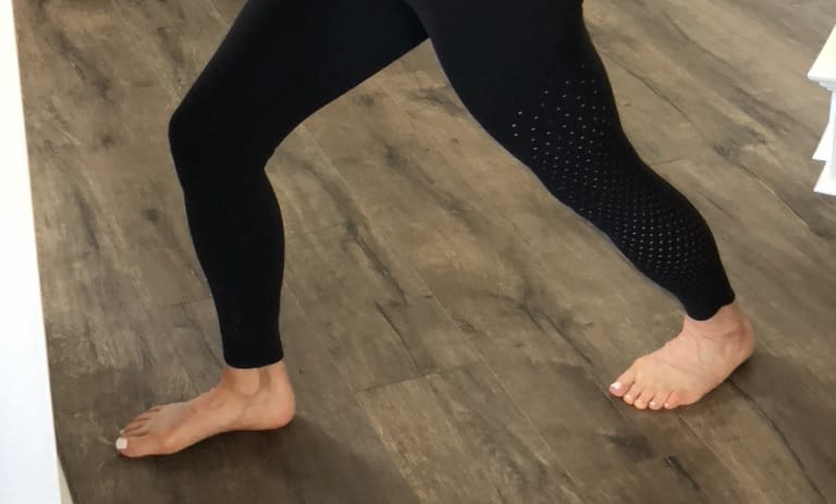Feet on the floor facing wall performing a heel press stretch