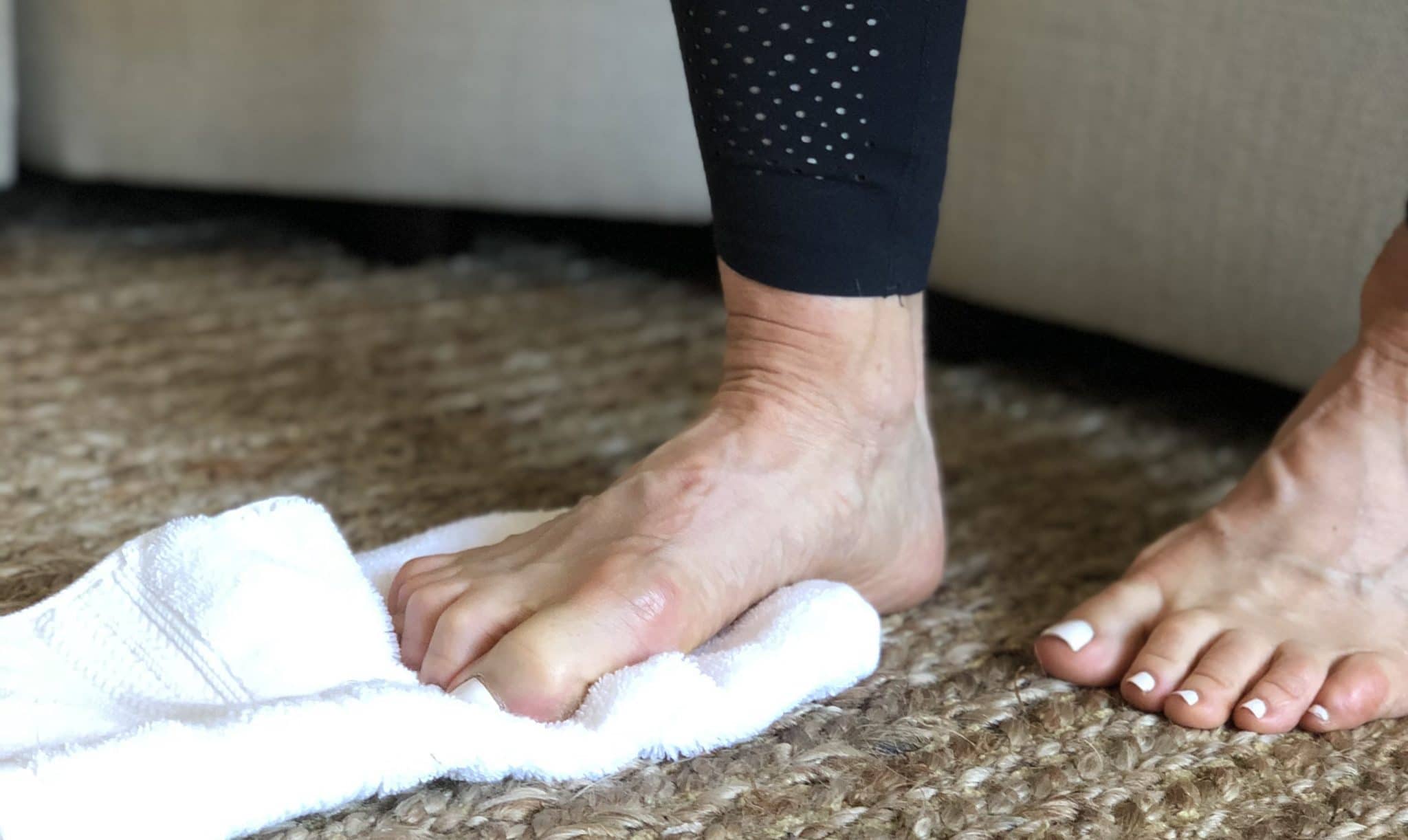 Close-up of foot squeezing washcloth on the floor