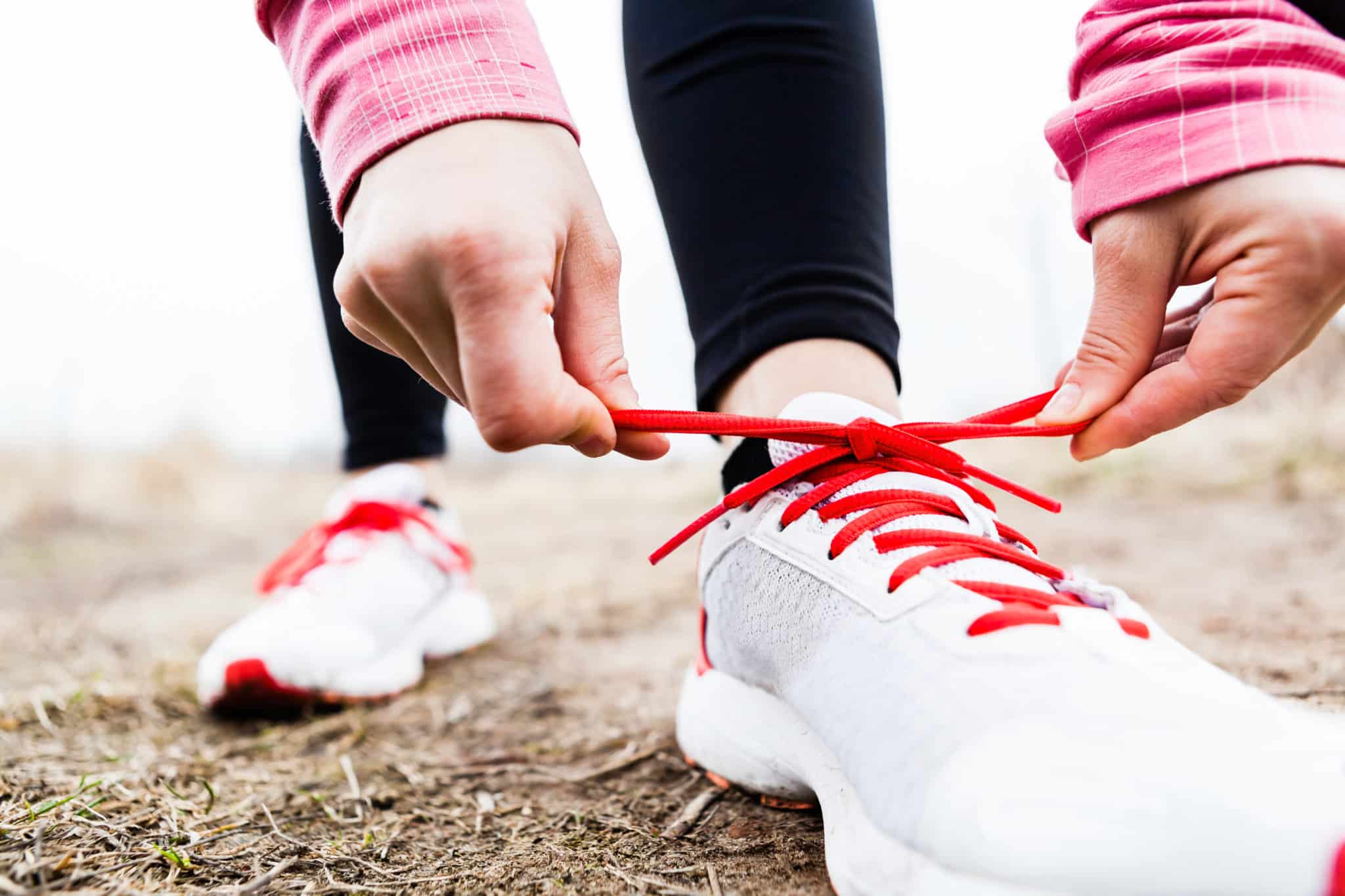 Close-up of woman tying tennis shoes outside