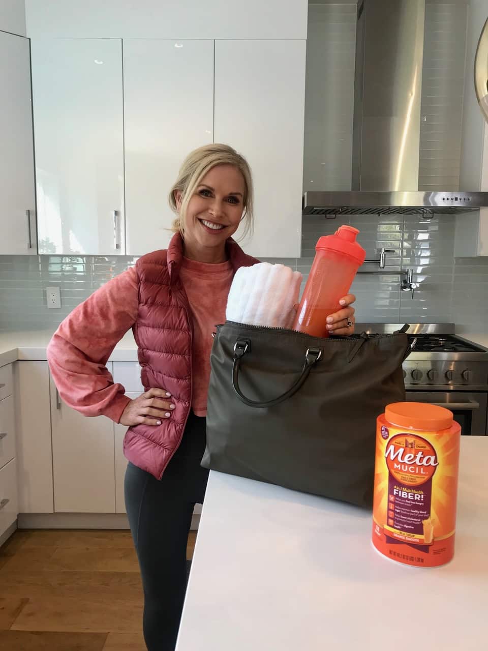 Chris Freytag holding a water bottle in the kitchen with Metamucil fiber on the kitchen counter.