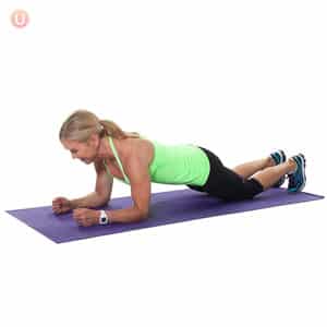 Chris Freytag doing a forearm plank modified from her knees on a purple yoga mat.