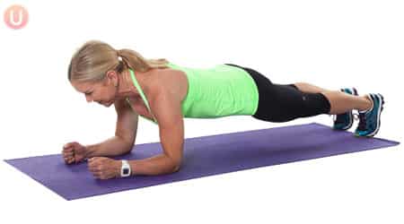 Chris Freytag doing a forearm plank on a purple yoga mat.